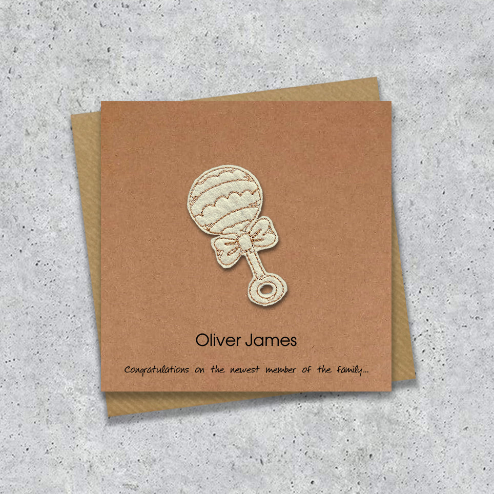 Kraft Baby boy card with embroidered baby's rattle design and personalised text