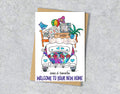 Greeting card with a colorful illustration of a car with furniture on top and text 'Welcome to your new home'.